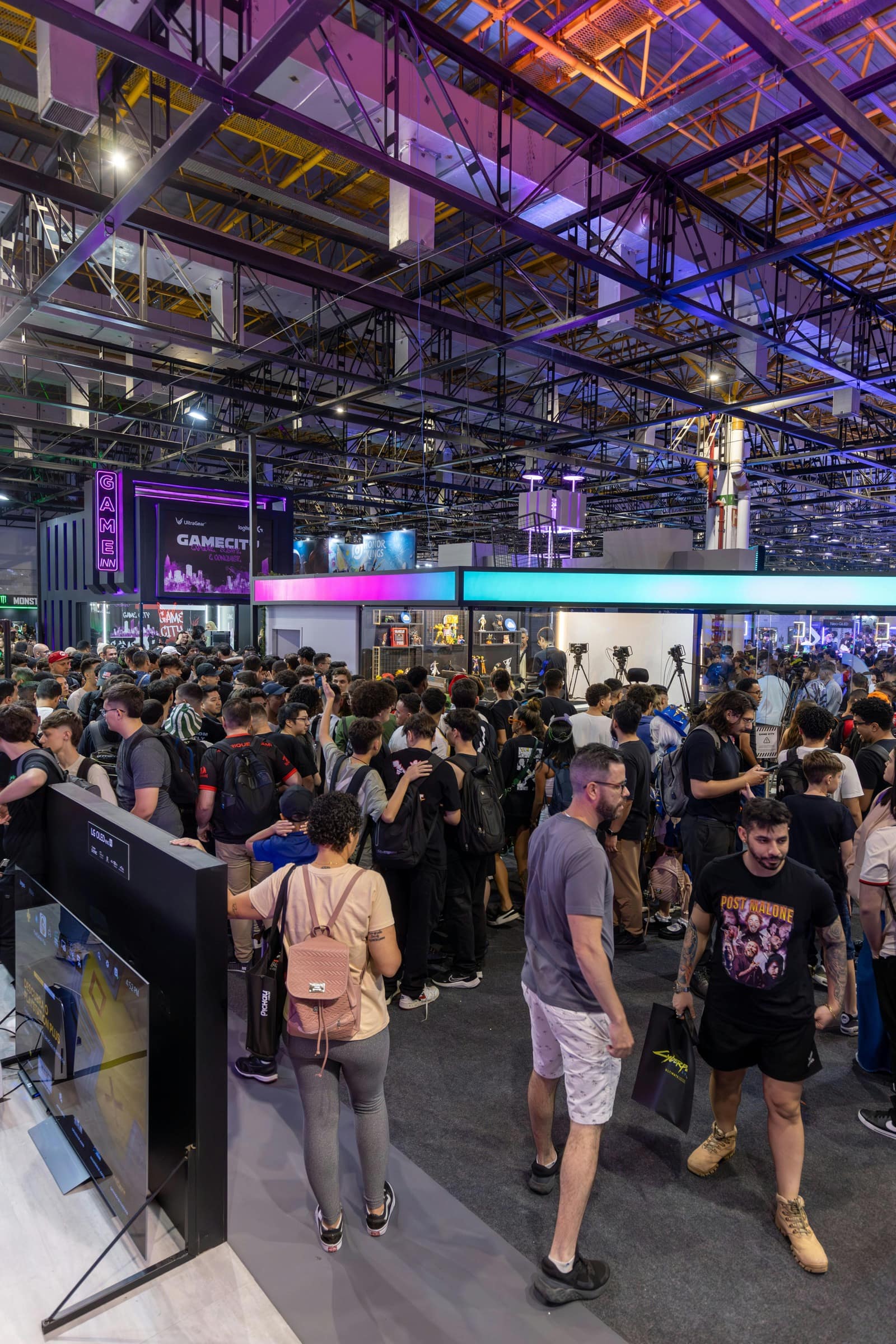 A crowded expo hall with attendees gathered around a brightly lit booth