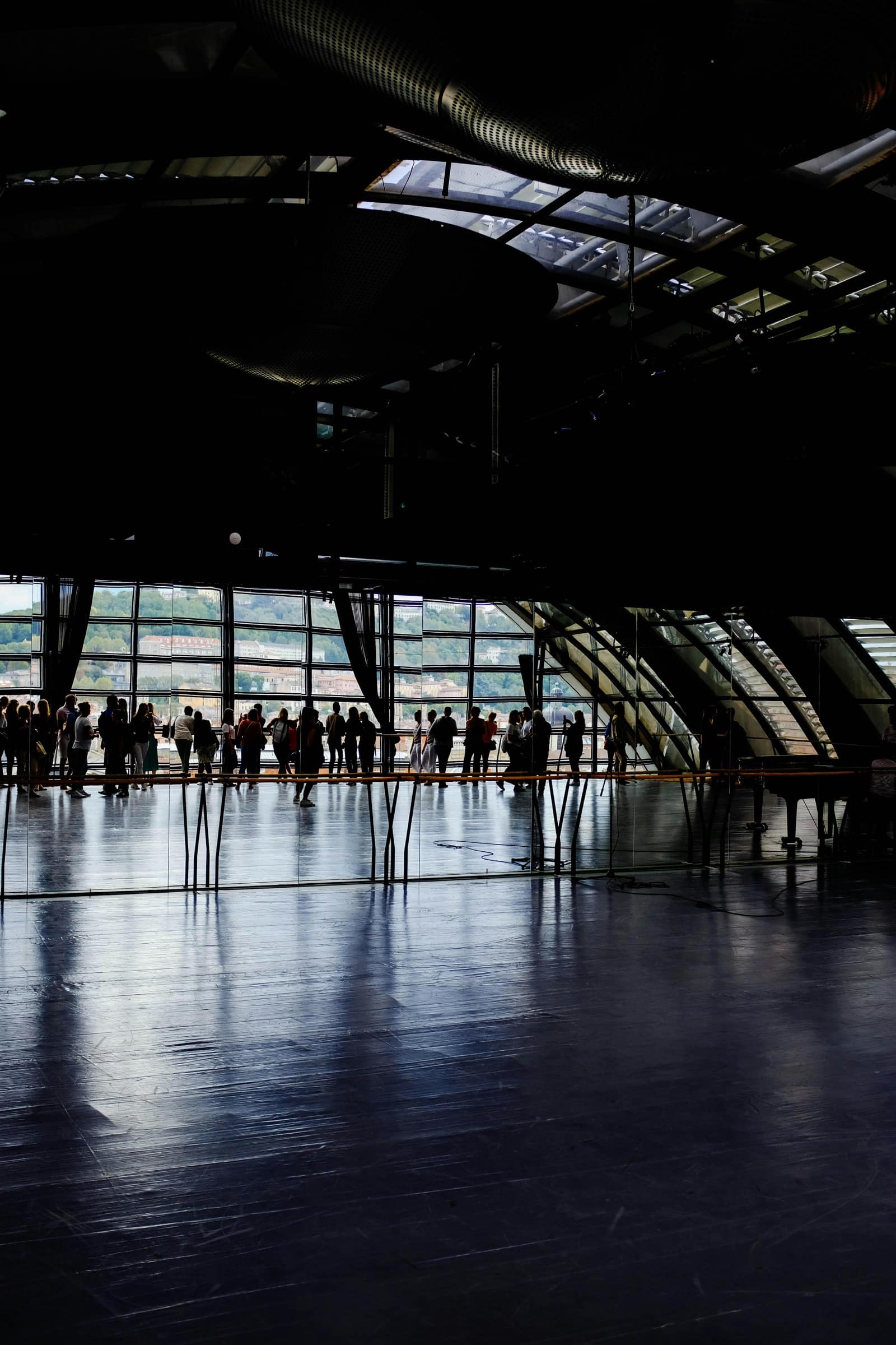 A spacious convention interior with silhouettes gathering near large windows